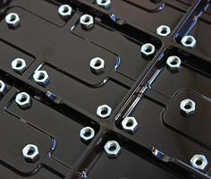 Steel nuts on a glossy plastic panel with rectangular compartments photo