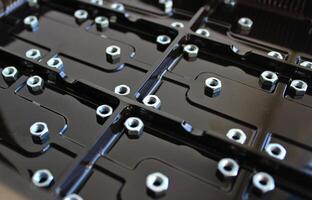 Separated Rectangular Elements With Screw Nuts On A Dark Varnished Plastic Panel photo