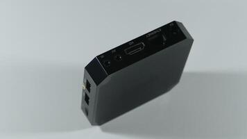 A square black TV tuner stands on an edge with visible slots and sockets for connection photo