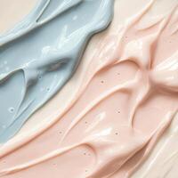Gentle smears of light blue and pale pink cosmetic cream create a soft visual. These represent skincare product textures, expertly swirled across a light background photo