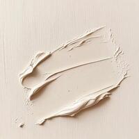 Close-up of a thick, smooth smear of light beige or off-white cream on a textured surface, suggesting skincare product, cosmetic application, or paint stroke photo