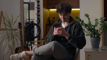 Happy Hispanic guy typing mobile phone screen at home client booking online smile user man using device technology hipster purchasing goods cyberspace app male chatting message email application net video