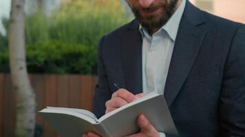Thoughtful Caucasian man university professor lecturer prepare for class lesson college education write notes outdoors in city businessman writing business ideas at paper notebook thinking thoughts video