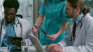 Doctors meeting multiethnic five people medical professionals healthcare discussion African Indian Caucasian surgeon team diverse medic colleagues use computer laptop analyzing xray health at clinic video