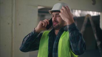 louco caucasiano cara falando Móvel telefone dentro construção controlador eletricista masculino faz-tudo discutindo conexão Smartphone construtor frustrado homem gritando capataz brigar raiva problema industrial trabalhos video