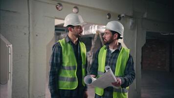 Satisfied Caucasian guys discussing draft handshake in construction contractors men technicians repairmen looking blueprint site colleagues builders architects teamwork building architecture project video