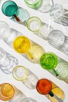 Colored Glasses pattern with shadow and sunlight reflection white background, minimal aesthetic top view summer still life, refraction at shine drink, caustic effect, green yellow clear glass cups photo