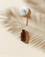 Liquid product packaging, dark glass bottle on sandy background with sunlight, shadow from palm leaf, natural pebble stone photo