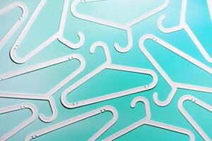 White Clothes hangers as creative minimal composition on pastel teal gradient background, Plastic racks creating modern and geometric aesthetic, top view, flatlay creative photo, smooth lines pattern photo