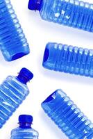 Clear single-use plastic water bottles isolated on white background close-up geometric pattern, minimal style, top view of bottled water, Pollution, environmental protection, plastic waste photo