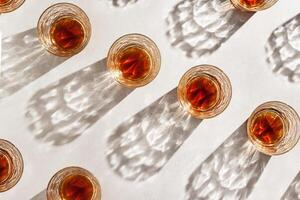 Whiskey Glasses with Shadow and sunlight Reflection on beige, glass strong alcohol, top view repeated pattern, aesthetic top view summer still life, refraction at crystal shine cups, caustics photo