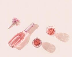 Bottle of rose wine, two glasses with drink, small bouquet of flowers in bright sunlight. Summer romance concept. photo