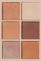 Eyeshadow neutral palette, mix of glitter, matte shades in beige, brown, red warm hues. Minimal top view pattern for beauty, makeup, cosmetic themes, Texture swatches eye shade or highlighter refills photo