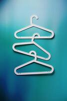 White Clothes hangers as creative minimal composition gradient background of teal and blue, Plastic racks creating modern and geometric aesthetic, top view photo vivid color, creative modern pattern