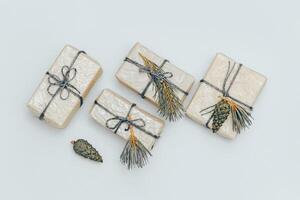 Christmas gift boxes wrapped in light recycled paper decorated with natural fir branches and green pine cones. photo