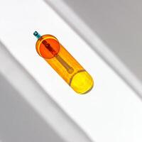 Orange colored glass mug with beautiful sunlight shadows on white. Top view yellow glass cup with Refraction at shiny drink, caustic effect, minimal aesthetic top view summer still life, copyspace photo