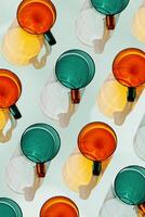 Orange and green Colored Glasses pattern with shadow and sunlight reflection on teal background, minimal aesthetic top view summer still life, refraction at shine drink, caustics photo