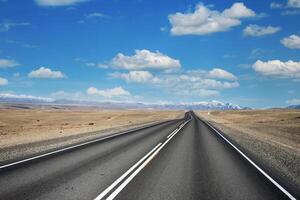 Beautiful view along Chuysky tract, Altai Republic, Russia, empty road, mountains and blue cloudy sky photo