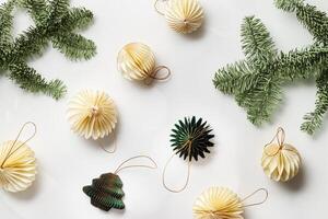 Minimal winter holidays top view composition with New Year paper festive ornaments cream beige balls, green Christmas Tree Ornament on light white background with golden bokeh light effects photo