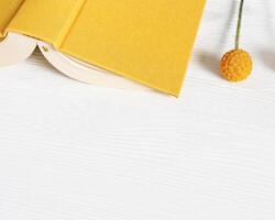 Concept digital detox, offline home activities as reading book. Top view with book in yellow cover on wood photo