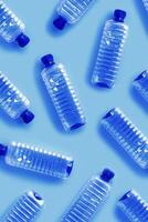 Pattern from Clear plastic water bottles with blue cap on light blue background with soft shadows, Minimal top view, themes of ecology, recycling, sustainable living, reduce disposable plastics photo