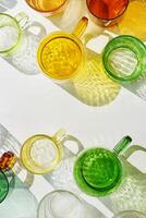 Colored Glasses pattern with shadows and sunlight reflection white background, minimal aesthetic top view summer still life, refraction at shine drink, caustic effect, green yellow glass cups photo