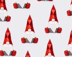 Volumetric paper Christmas gnomes in red pointed hat on light background, polygonal figure dwarf photo