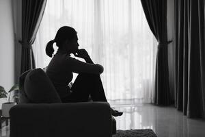A depressed woman sits on a sofa. photo