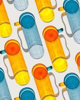 Vibrant of orange and blue glass cups on white background, casting artistic light reflections and shadows in natural sunlight. Summer drink concept, minimal pattern of transparent glasses photo