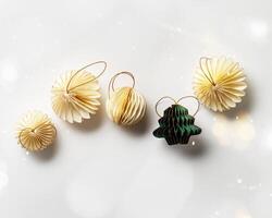 New Year decorative ornaments and green Christmas tree shape bauble on white background, Minimal layout with paper festive decor beige balls, green Christmas Tree Ornament, modern decor, top view photo
