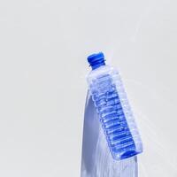 Blue plastic bottles at sunlight shadow on grey white background, top view empty plastic bottle for water half litre, minimal design. Pollution, plastic garbage, environmental protection concept photo