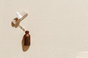 Serum or Liquid Collagen dropper bottle on sand background with sunlight, shadow from palm leaves, natural wooden stone photo