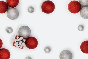 Christmas frame with sparkly red and silver Christmas balls and small gift box or present on white background photo