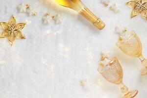New Year holiday flat lay, Christmas ornaments, sparkling wine bottle, peach color glasses on white fur background with bokeh lights. Glittering festive decor Christmas stars copy space photo