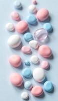 A collection of white, pink, and blue candy spheres of various sizes on a light blue background photo
