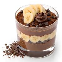 Dark chocolate mousse layered with banana slices in a transparent glass, topped with chocolate chips and banana curls, isolated photo