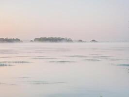 Serene Foggy Riverbank with Soft Pastel Tones photo