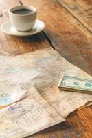 Crumpled city map, phrasebook, and currency rest on a cafe table with warm sunlight streaming in photo