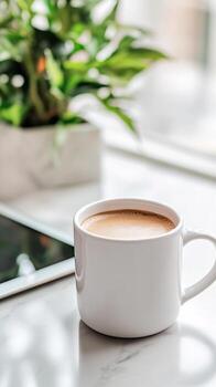 Sleek coffee mug and tablet displaying news sit on a marble countertop, surrounded by soft morning light photo