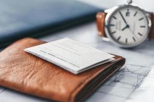 A train ticket rests on a leather wallet beside a watch, ready for an exciting journey ahead in the morning photo