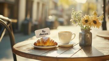 Relax at a sunny outdoor cafe with a croissant, cappuccino, and flowers, embracing a device-free moment for wellness photo