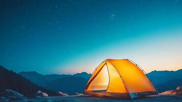 A tent glows softly, set against a breathtaking mountain landscape at night photo