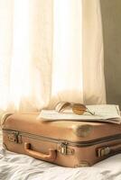 A suitcase sits on a bed, almost packed with a passport, boarding pass, and sunglasses ready for travel photo