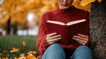 Autumn reading session of a person under a tree park setting relaxing outdoor scene photo