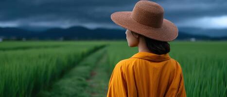 Woman walking through rice field path under cloudy sky in nature landscape photo