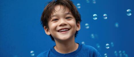 Joyful asian boy playing with soap bubbles outdoor portrait bright blue background photo
