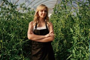 Standing with ,arms crossed. Beautiful woman is in the greenhouse photo
