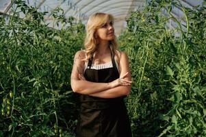 Standing ,with arms crossed. Beautiful woman is in the greenhouse photo
