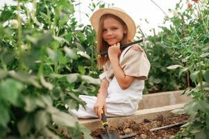 Holding garden tools... Little ,girl is in the greenhouse photo
