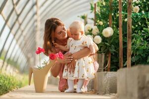 Little cute baby. Mother and daughter are,, in the greenhouse photo